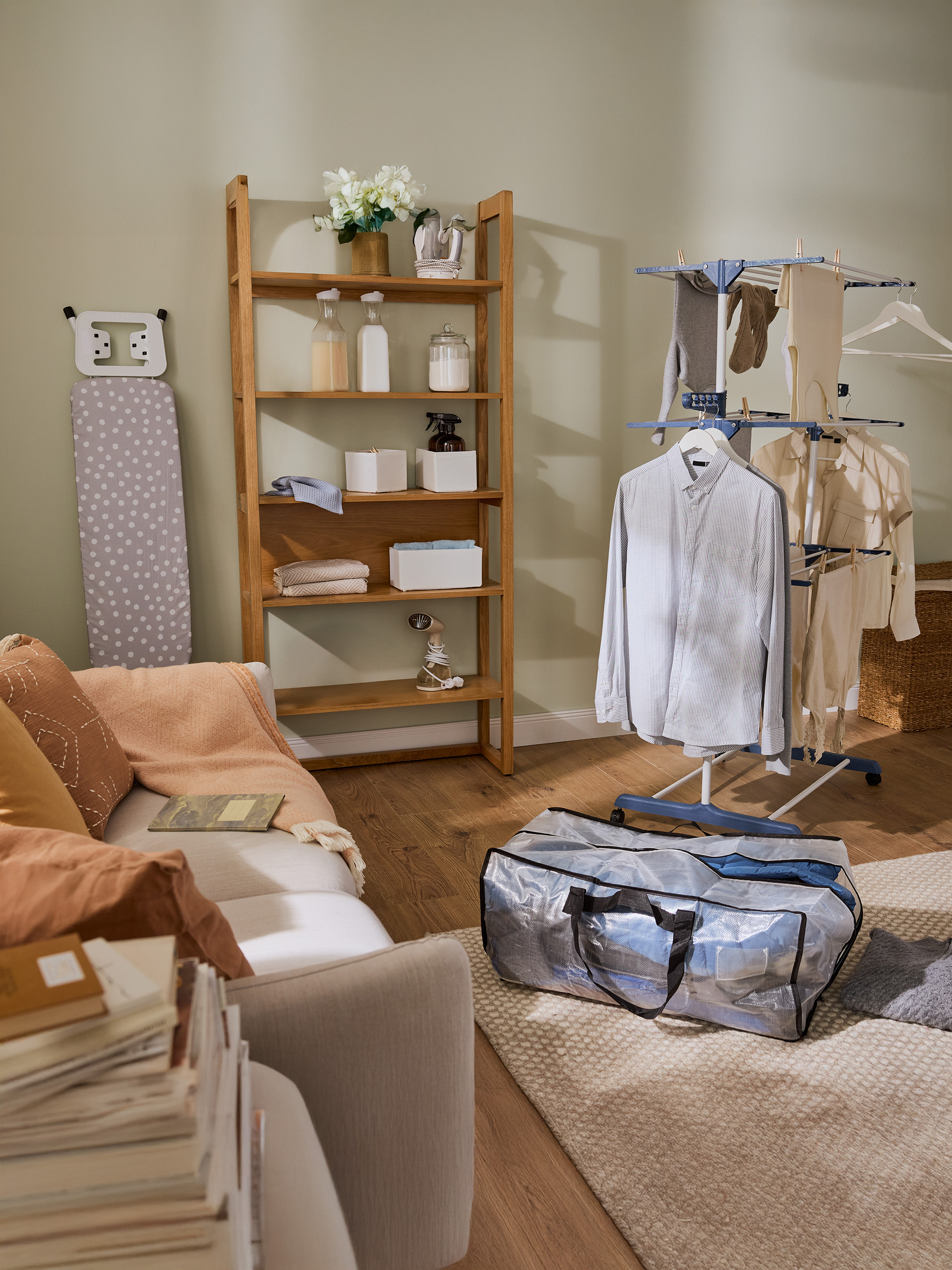 Wasruimte met houten plank, strijkplank en wasrek met kleding.