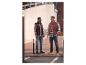 Twee mannen in geruite overhemden, bodywarmers, jeans en casual schoenen op een stadsstraat.