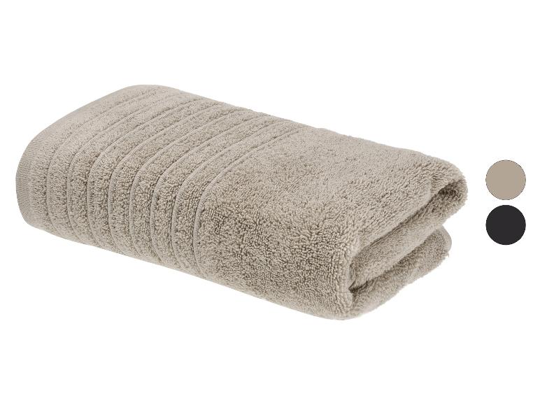 Gevouwen beige handdoek met geribbelde textuur, toont twee kleurstalen: beige en zwart.
