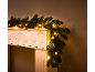 Kerstslinger met warmwitte lampjes over een witte schouw.