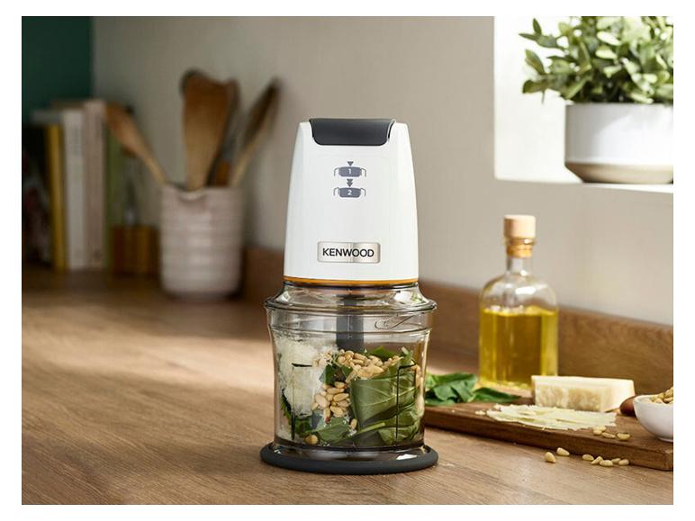 Witte hakmolen met pesto-ingrediënten op een houten aanrecht.