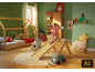 Meisje glijdt van houten glijbaan in kinderkamer met kerstversiering.