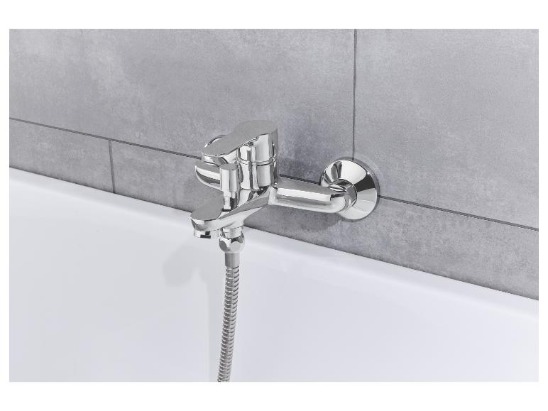 Chromen badkraan met handdouche, gemonteerd op grijze tegels.