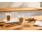 Twee koffieglazen met macarons en suiker op een houten tafel.