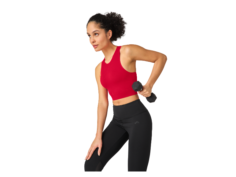 Vrouw sporten in leggings en sporttop, dumbbells in de hand.