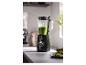 Blender met groene smoothie op aanrecht, met gesneden limoenen en noten ernaast.