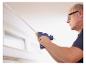 Man gebruikt LIVARNO® CG270 draadloos lijmpistool om een strip aan het plafond te bevestigen.