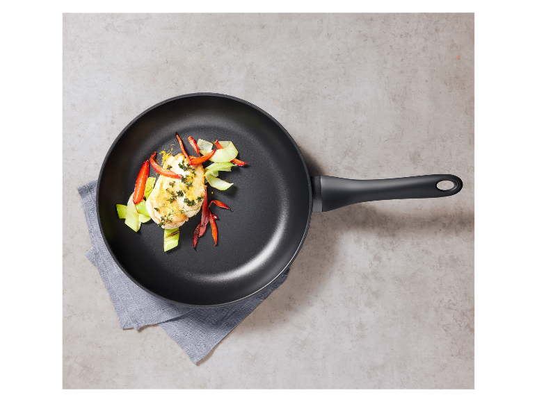 Een zwarte pan met gegrilde kip en groenten.