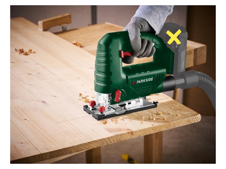 Accu decoupeerzaag met stofzuiger op hout, vastgehouden door een persoon met handschoen.
