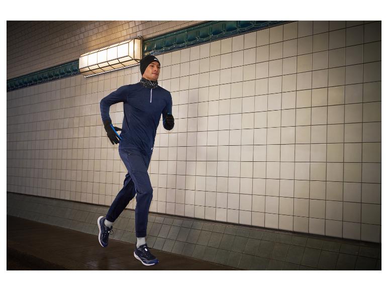 Man rent in een tunnel, draagt een hoodie, broek en hardloopschoenen.