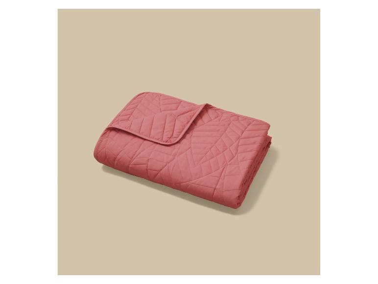 Roze gewatteerde deken of sprei met geometrisch patroon.