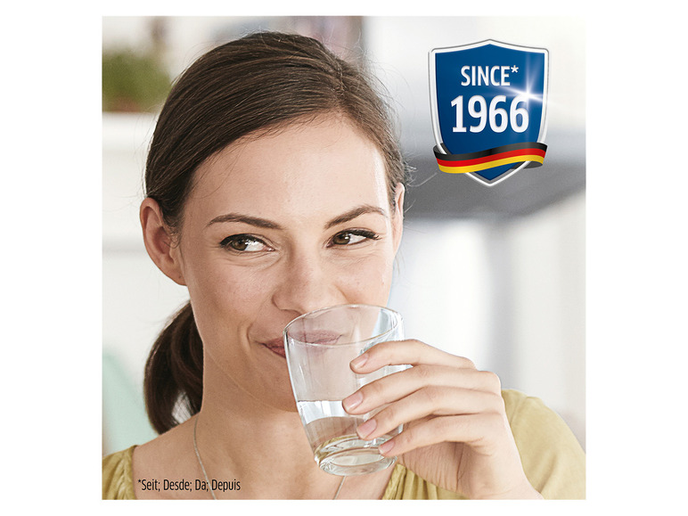 Een vrouw drinkt water uit een glas, met een logo met de tekst 'Since 1966' ernaast.