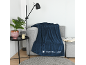 Donkerblauwe plaid op een grijze bank met een lamp en een kamerplant.
