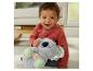 Blije baby met een pluchen koala knuffel met een gloeiende buik, zittend op een vloerkleed.
