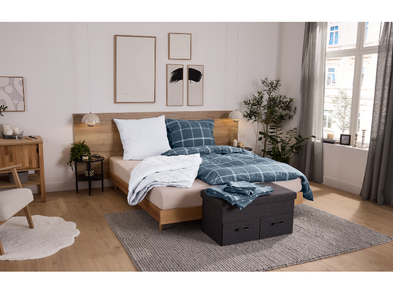 Gezellige slaapkamer met houten bed, blauw geruit beddengoed en grijs vloerkleed.