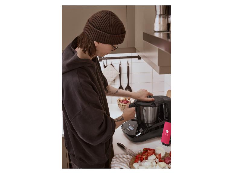 Persoon bereidt maaltijd met Monsieur Cuisine slimme keukenmachine en verse groenten.