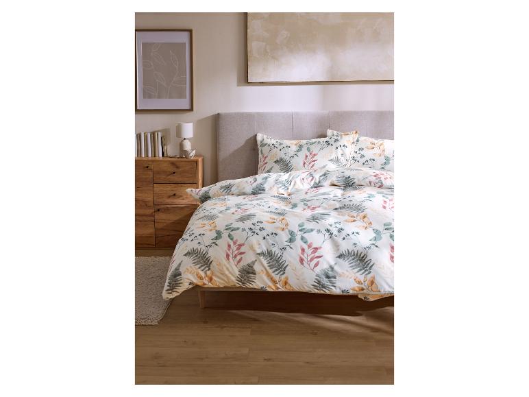 Slaapkamer met bloemenbeddengoed, houten nachtkastje en kunst aan de muur