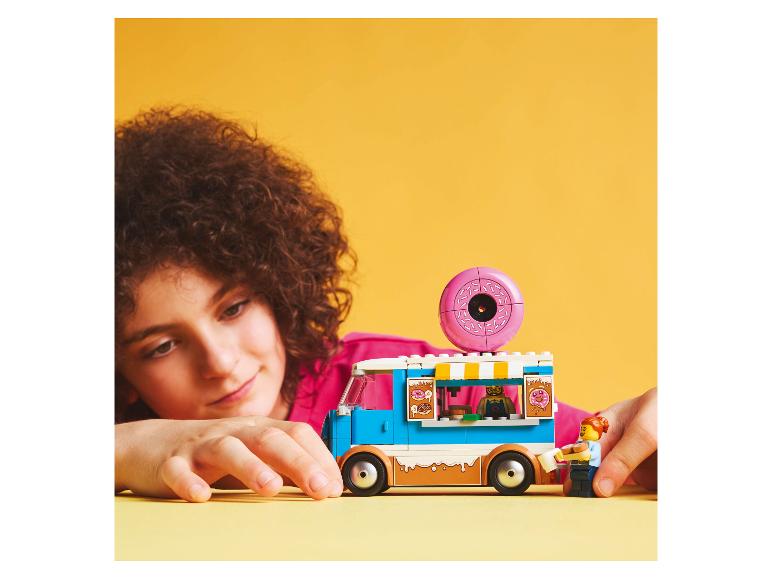 Een kind speelt met een LEGO Friends donut foodtruck set.