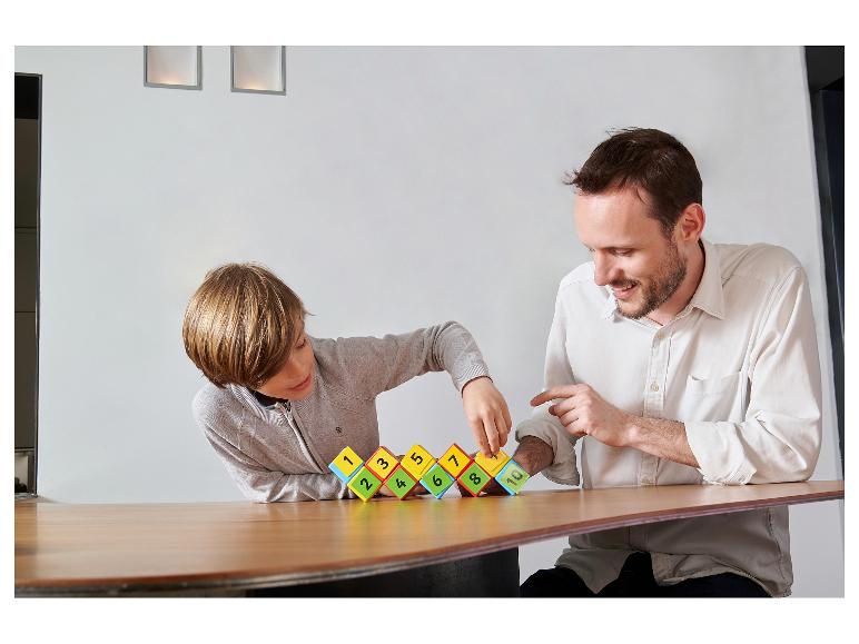 Vader en kind spelen met genummerde bouwblokken op een houten tafel.