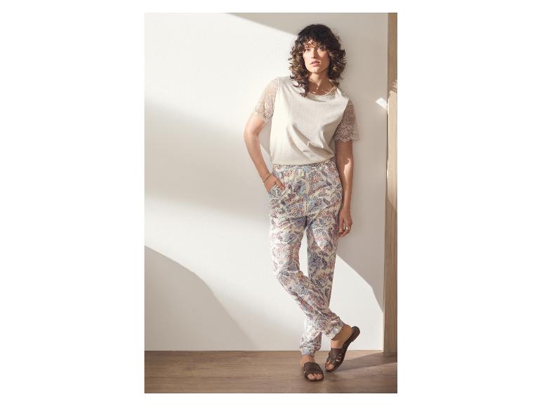Vrouw in beige T-shirt met kanten mouwen en bedrukte broek.