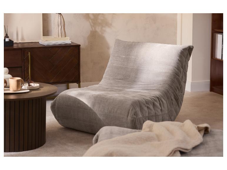 Grijze, comfortabele fauteuil in een woonkamer met een donkerhouten kast en salontafel.
