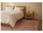 Slaapkamer met licht houten bed, wit beddengoed en roze vloerkleed
