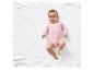 Baby op een witte deken in een roze romper.