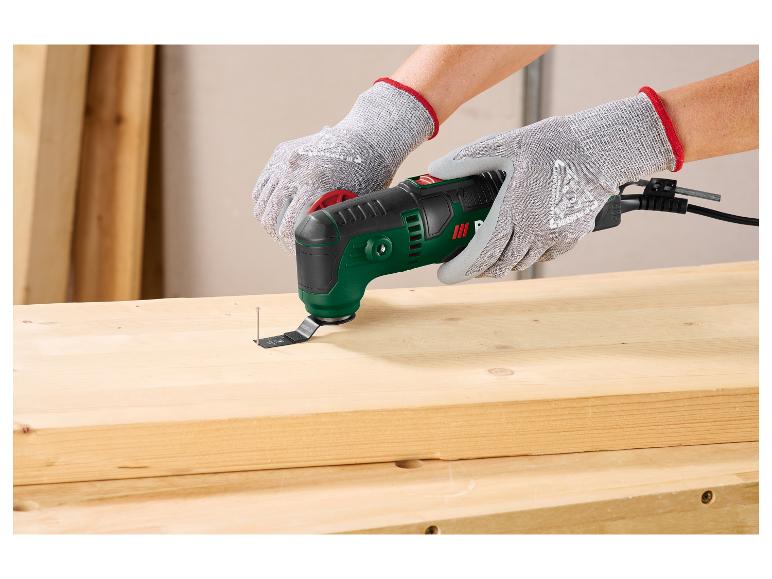 Persoon met handschoenen gebruikt een multitool om een spijker uit een houten plank te verwijderen.