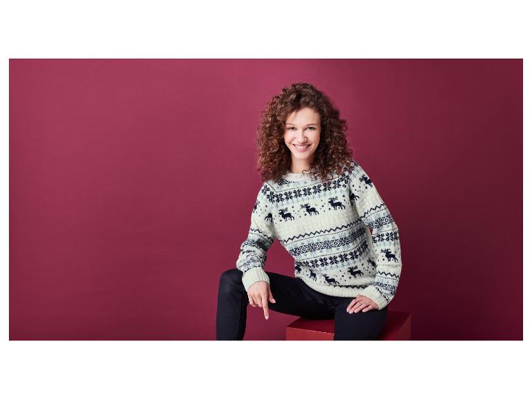 Een vrouw draagt een crèmekleurige trui met kerstmotief