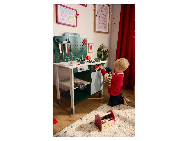 Een kind speelt met een Parkside-werkbank en gereedschapset op een tapijt.