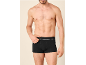 Man met ontbloot bovenlijf draagt zwarte boxershort met witte band.