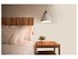 Slaapkamer met houten hoofdbord, wit beddengoed, kussens en nachtkastje met lamp.