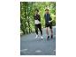 Twee hardlopers in sportkleding, jas, vest en broek, rennend op een weg.