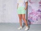 Model met lichtgroene shorts, wit T-shirt en witte sneakers.