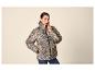 Vrouw in luipaardprint pufferjack en jeans, poserend met hand in zak.