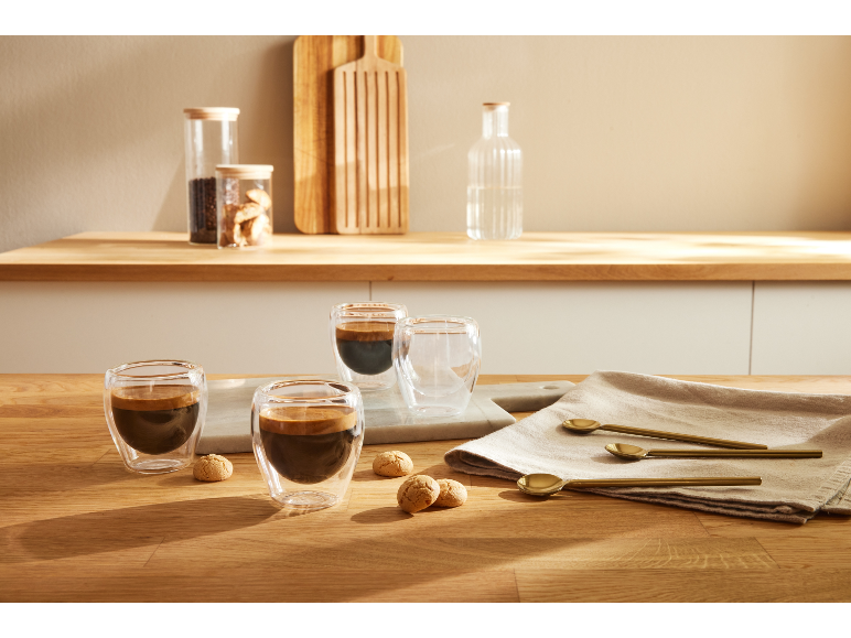 Twee espressokopjes met koekjes op een houten tafel.