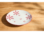 Wit bord met rode sneeuwvlokken op een houten tafel.