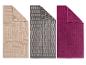 Drie badhanddoeken: beige met geometrisch patroon, grijs met baksteenpatroon en effen fuchsia.