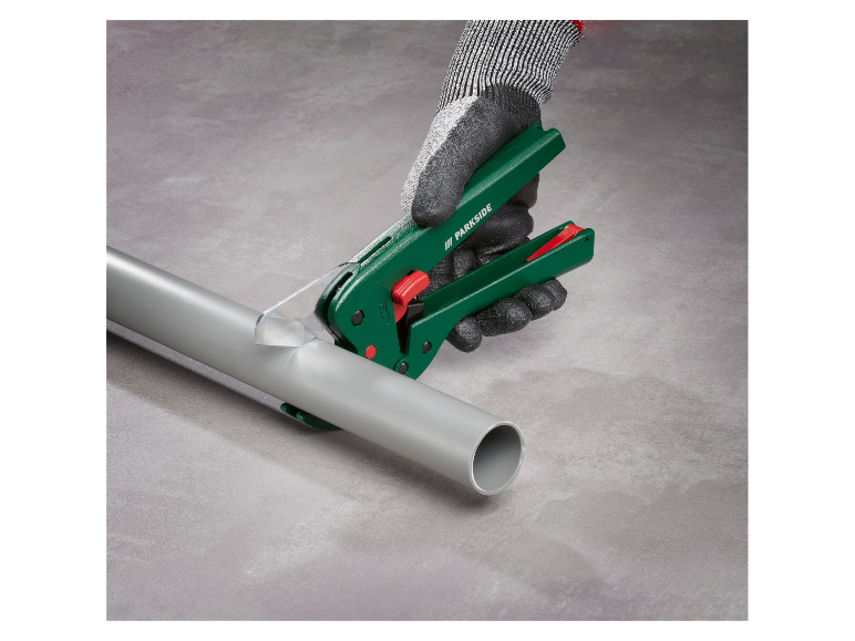 Een paar grijze handschoenen houden een Parkside gereedschap vast om PVC-buizen te snijden.