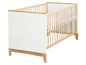 Een wit babybedje met houten spijlen en poten.