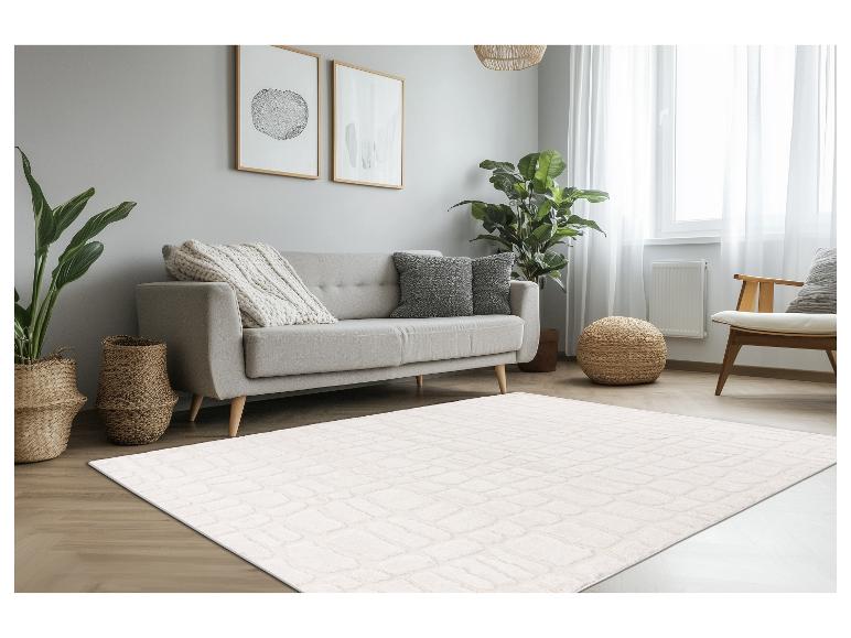 Crèmekleurig rechthoekig vloerkleed met textuurpatroon in een lichte, moderne woonkamer.