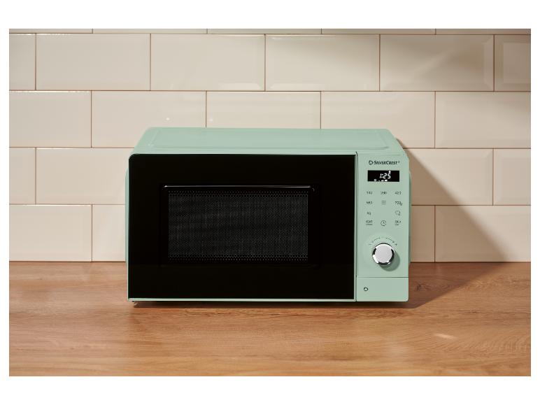 Mintgroene magnetron met digitaal display en bedieningselementen in een moderne keuken.