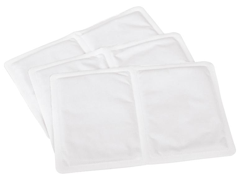 Vier witte warmtepads of handwarmers, in een overlappende stapel.