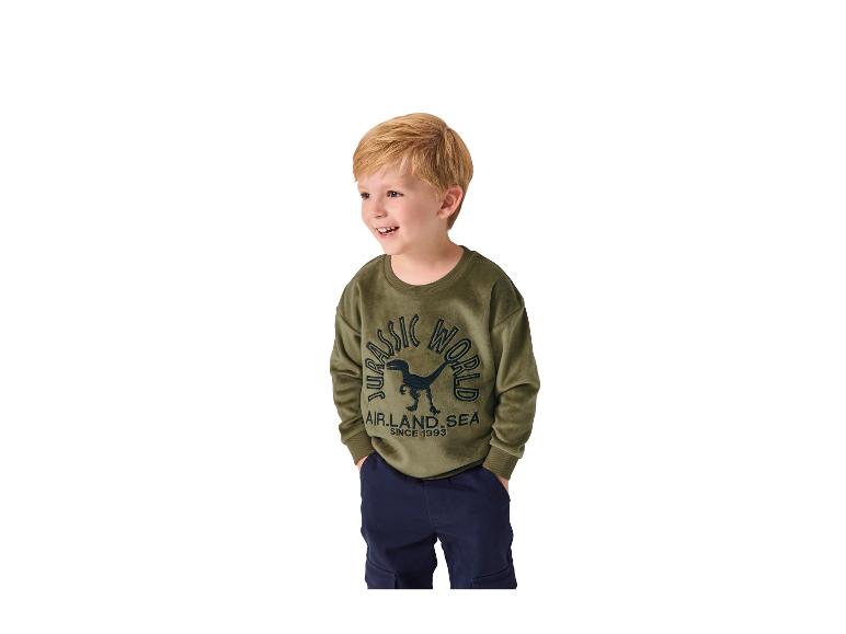 Jongen in een groen 'JURASSIC WORLD' sweatshirt en donkerblauwe broek.