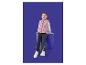 Meisje in roze vest met strikjes, wit shirt met lange mouwen en donkere jeans zittend op een blauwe kruk.