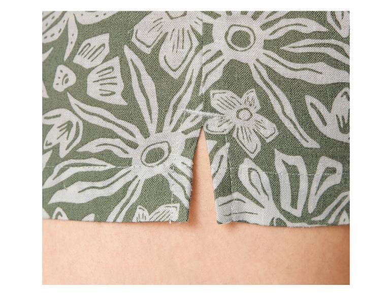 Groene stof met wit bloemenpatroon en een split in de zoom.