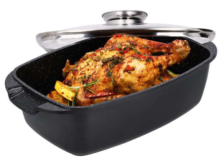 Geroosterde kip met kruiden en citroen in een zwarte braadslede met glazen deksel