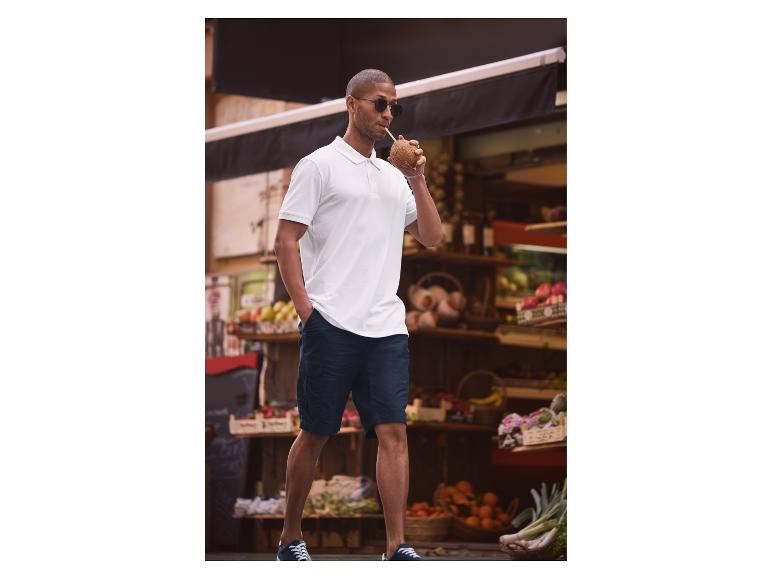 Wit poloshirt, donkerblauwe shorts en kokosnoot: casual zomerse stijl.