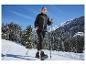 Vrouw in CRIVIT thermo softshell jas en met stokken wandelt op besneeuwd bergpad.