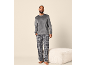 Man in grijze velours trui en geruite pyjamabroek.